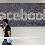 FILE - In this March 15, 2013, file photo, a Facebook employee walks past a sign at Facebook headquarters in Menlo Park, Calif. Facebook reports financial results on Wednesday, April 27, 2016. (AP Photo/Jeff Chiu, File)