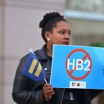 Cassandra Thomas of Human Rights Campaign holds a sign advocating the repeal of HB2 as Executive Director Chad Griffin, President of Human Rights Campaign and Executive Director of Equality NC, Chris Sgro, discuss the North Carolina election results at the Government Center on Wednesday, Dec. 7, 2016, in Charlotte. (Brian Gomsak/AP Images for Human Rights Campaign)