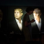 A journalist  writes a material as she watches a live telecast of the U.S. presidential election standing at portraits of Hillary Clinton, Donald Trump and Vladimir Putin in the Union Jack pub in Moscow, Russia, Wednesday, Nov. 9, 2016. Russia's lower house of parliament is applauding the election of Donald Trump as U.S. president. (AP Photo/Alexander Zemlianichenko)
