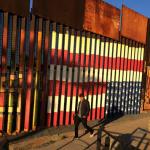People pass graffiti along the border structure  in Tijuana, Mexico, Wednesday, Jan. 25, 2017.  President Donald Trump moved aggressively to tighten the nation's immigration controls Wednesday, signing executive actions to jumpstart construction of his promised U.S.-Mexico border wall and cut federal grants for immigrant-protecting "sanctuary cities." (AP Photo/Julie Watson)