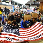 Demonstrators sit down in the concourse and hold a sign that reads "We are America." More than 1,000 people gather at Seattle-Tacoma International Airport, Saturday, January 28 to protest President Trump's immigration ban.President Trump signed an executive order Friday that bars citizens from Iraq, Syria, Iran, Libya, Somalia, Sudan and Yemen from entering the U.S. for the next 90 days and suspends the admission of all refugees for 120 days. (AP Photo/seattlepi.com, Genna Martin)