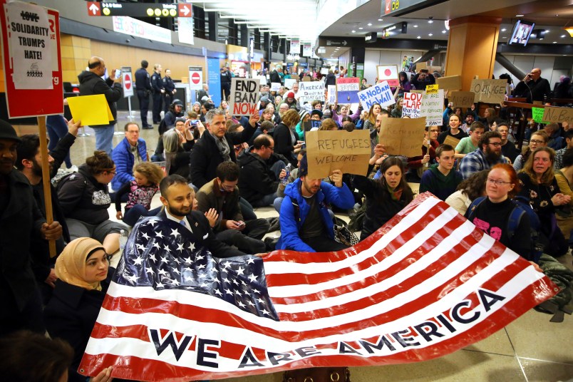Demonstrators sit down in the concourse and hold a sign that reads "We are America." More than 1,000 people gather at Seattle-Tacoma International Airport, Saturday, January 28 to protest President Trump's immigration ban.President Trump signed an executive order Friday that bars citizens from Iraq, Syria, Iran, Libya, Somalia, Sudan and Yemen from entering the U.S. for the next 90 days and suspends the admission of all refugees for 120 days. (AP Photo/seattlepi.com, Genna Martin)