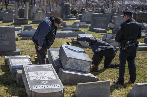 Northeast Philadelphia Police Dective Timothy McIntyre, center, dusts one of the many headstones that were knocked down, for fingerprints as Dectective Nick McReynolds, left, looks on on Sunday afternoon. Vandals strike the Jewish Mount Carmel Cemetery at Frankford and Cheltenham Avenues. Awaiting police details. 02/26/2017  MICHAEL BRYANT / Staff Photographer