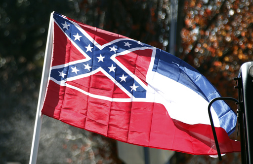 FILE - In this Tuesday, Jan. 19, 2016 file photo, a state flag of Mississippi is unfurled by Sons of Confederate Veterans and other groups on the grounds of the state Capitol in Jackson, Miss., in support of keeping the Confederate battle emblem on the state flag. Mississippi attorney Carlos Moore is trying to revive his lawsuit challenging the Confederate battle emblem on the state flag. Moore filed notice Wednesday, Sept. 14, 2016, that he will appeal a federal judge’s decision that dismissed the suit. The Mississippi flag has had the Confederate emblem since 1894, and voters chose to keep it in a 2001 referendum. (AP Photo/Rogelio V. Solis)