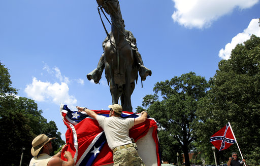 FILE - In this July 12, 2015, file photo, Mike Goza, left, helps Mike Junor drape a Confederate battle flag over the base of the statue and tomb of Nathan Bedford Forrest, a rebel general, slave trader and early Ku Klux Klan member, at Health Sciences Park in Memphis, Tenn. State House members said they were surprised that they unwittingly passed a resolution honoring Forrest on April 13, 2017 (Mike Brown/The Commercial Appeal via AP, file)