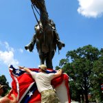 FILE - In this July 12, 2015, file photo, Mike Goza, left, helps Mike Junor drape a Confederate battle flag over the base of the statue and tomb of Nathan Bedford Forrest, a rebel general, slave trader and early Ku Klux Klan member, at Health Sciences Park in Memphis, Tenn. State House members said they were surprised that they unwittingly passed a resolution honoring Forrest on April 13, 2017 (Mike Brown/The Commercial Appeal via AP, file)