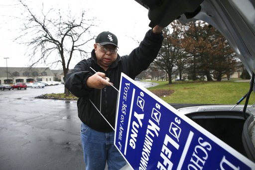 High School District 211 school board candidate Ed Yung, who supports the current agreement, unloads yard signs from the trunk of his car to post near polling places on Monday, April 3, 2017 in Hoffman Estates. (Stacey Wescott/Chicago Tribune)