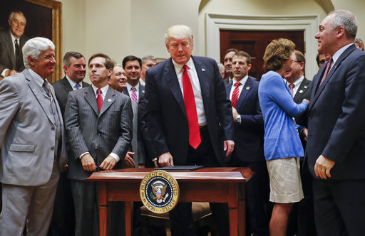 President Donald Trump, center, surrounded by Congressional and business leaders, gets up from his seat after signing an Executive Order in the Roosevelt Room of the White House in Washington, Friday, April 28, 2017. The Executive Order directs the Interior Department to begin review of restrictive drilling policies for the outer-continental shelf. (AP Photo/Pablo Martinez Monsivais)