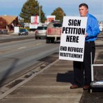FILE--In this Dec. 8, 2015, file photo, Rick Martin, the head of the Committee to End the Colle of Southern Idaho’s Refugee Center, works to gather petition signatures in Twin Falls, Idaho.  . Twin Falls City Council members on Monday approved the “neighborly community” resolution affirming its role as a welcoming city rather than adopt policies defying U.S. immigration officials. (AP Photo/Otto Kitsinger, file)