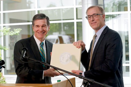 North Carolina Gov. Roy Cooper, left, and Wilson Ervin, Chair of the Credit Suisse Americas Foundation pose with the State Seal during a news conference at Credit Suisse in Morrisville, N.C., Tuesday, May 9, 2017. Credit Suisse plans to add up to 1200 jobs at its North Carolina technology hub. The jobs projection comes five weeks after North Carolina partially repealed a state law limiting LGBT rights. (AP Photo/Gerry Broome)