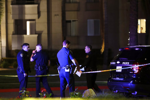 San Diego police officers stand in front of a La Jolla apartment after a shooting Sunday, April 30, 2017, in San Diego. San Diego Mayor Kevin Faulconer looks on at right. Police shot and killed a 49-year-old man suspected of shooting seven people Sunday at a birthday pool party in an apartment complex near the University of California, San Diego, authorities said. (AP Photo/Gregory Bull)