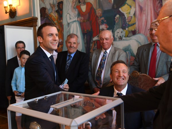 French President Emmanuel Macron, left, shakes hands wit a pooling station official after casting his ballot in the second round of the French parliamentary elections, in Le Touquet, northern France, Sunday, June 18, 2017. (Christophe Archambault/Pool Photo via AP)