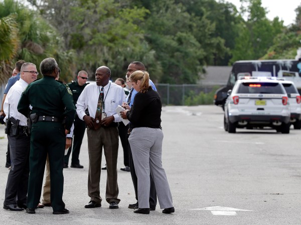Authorities confer, Monday, June 5, 2017, near Orlando, Fla. Law enforcement authorities said there were "multiple fatalities" following a Monday morning shooting in an industrial area near Orlando. On its officials Twitter account Monday morning, the Orange County Sheriff's Office said the "situation" has been contained. They said Orange County Sheriff Jerry Demmings will make a statement "as soon as info is accurate." (AP Photo/John Raoux)