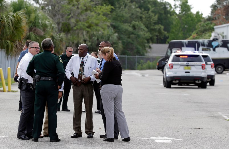 Authorities confer, Monday, June 5, 2017, near Orlando, Fla. Law enforcement authorities said there were "multiple fatalities" following a Monday morning shooting in an industrial area near Orlando. On its officials Twitter account Monday morning, the Orange County Sheriff's Office said the "situation" has been contained. They said Orange County Sheriff Jerry Demmings will make a statement "as soon as info is accurate." (AP Photo/John Raoux)