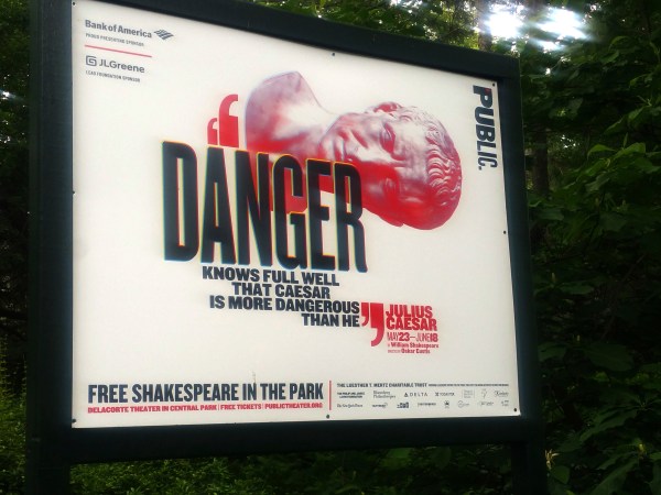 In this June 7, 2017 photo, "Danger knows full well that Caesar is more dangerous than he," reads a sign promoting The Public Theater's production of Julius Caesar in New York's Central Park. Gregg Henry, the actor who starred in Shakespeare's "Julius Caesar" on a New York stage wears a Donald Trump-like costume to play the powerful Roman politician betrayed by his top aide and knifed to death. (AP Photo/Verena Dobnik)
