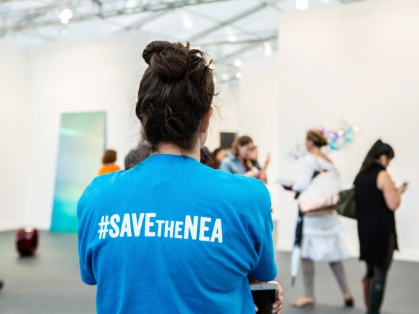 New York, NY - 5 May 2017. The opening day of the Frieze Art Fair, showcasing modern and contemporary art presented by galleries from around the world, on Randall's Island in New York City. A woman wears a T-shirt captioned "#SAVEtheNEA," as part of a movement to fight cuts in funding for the National Endowment for the Arts.