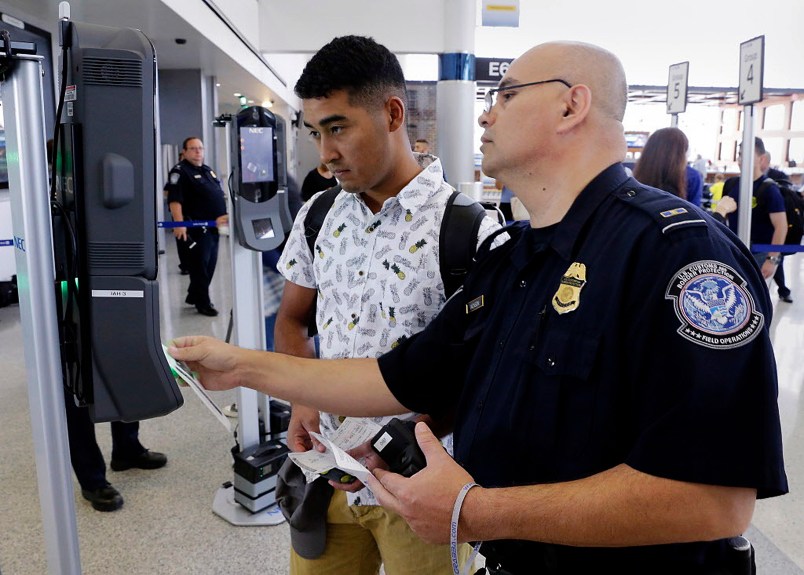 U.S. Customs and Border Protection officer Sanan Jackson (right) helps a passenger (no ID) navigate the new face recognition kiosks at United Airlines gate E7 for a flight to Tokyo at Bush Intercontinental Airport in Houston, TX, June 29, 2017. (Michael Wyke / For the  Chronicle)
