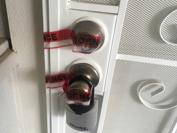 Red evidence tape covers part of the door leading to the condo where Ikaika Kang lives in Waipahu, Hawaii. The 34-year-old Army sergeant stationed in Hawaii is being held on terrorism charges after the FBI claims he tried to get secret military documents to the Islamic State. (AP Photo/Jennifer Sinco Kelleher)