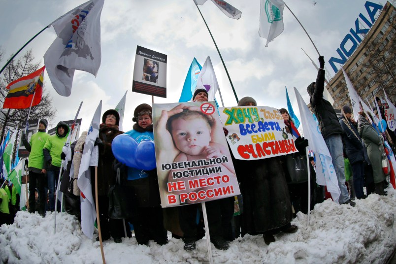 Demonstrators hold posters reading "There is no place for juvenile justice in Russia," "I want all children be happy" during a massive rally to back the ban on U.S. adoptions of Russian children in Moscow, Saturday, March 2, 2013. Russia voiced strong skepticism Saturday about the U.S. autopsy on Max Shatto, a 3-year-old adopted Russian boy in Texas and demanded further investigation as thousands rallied in Moscow to support the Kremlin ban on U.S. adoptions of Russian children. (AP Photo/Alexander Zemlianichenko)