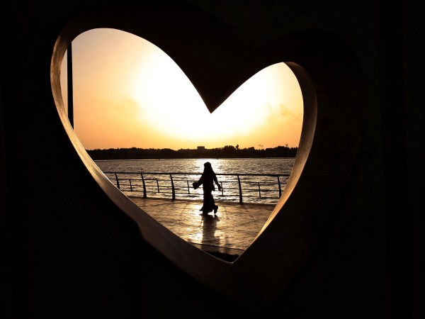 FILE -- In this Sunday, May 11, 2014 file photo, a Saudi woman seen through a heart-shaped statue walks along an inlet of the Red Sea in Jiddah, Saudi Arabia. A young Saudi woman has sparked a sensation online by posting a video of herself in a miniskirt and crop top walking around in public, with some Saudis calling for her arrest and others rushing to her defense. (AP Photo/Hasan Jamali, File)