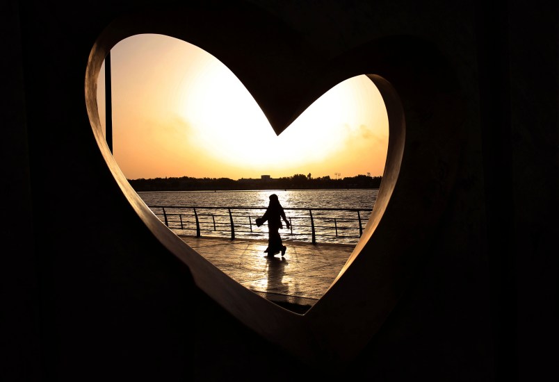 FILE -- In this Sunday, May 11, 2014 file photo, a Saudi woman seen through a heart-shaped statue walks along an inlet of the Red Sea in Jiddah, Saudi Arabia. A young Saudi woman has sparked a sensation online by posting a video of herself in a miniskirt and crop top walking around in public, with some Saudis calling for her arrest and others rushing to her defense. (AP Photo/Hasan Jamali, File)