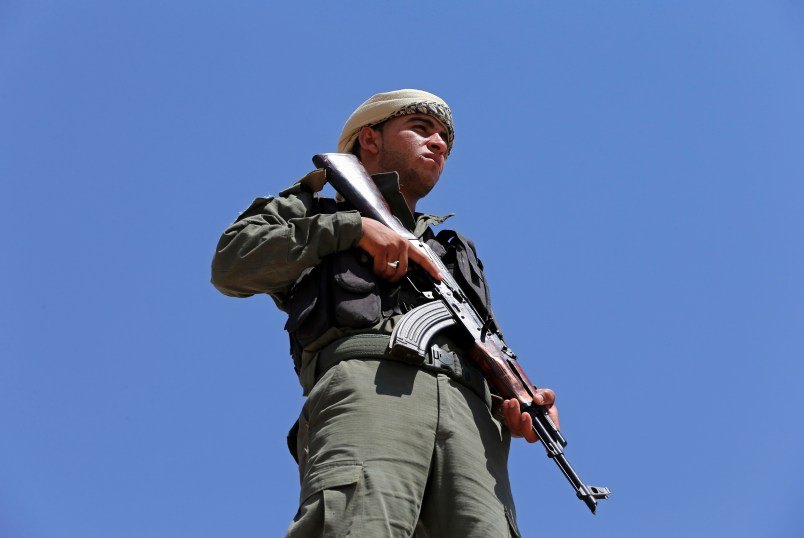A Syrian Internal Security Forces soldier, stand guards as his comrades attend their  graduation ceremony, at Ain Issa desert base, in Raqqa province, northeast Syria, Thursday, July 20, 2017. Some 250 residents of Syria's Raqqa province are the latest batch to graduate from a brief U.S-training course that is preparing an internal security force to hold and secure areas as they are captured from Islamic State militants.(AP Photo/Hussein Malla)