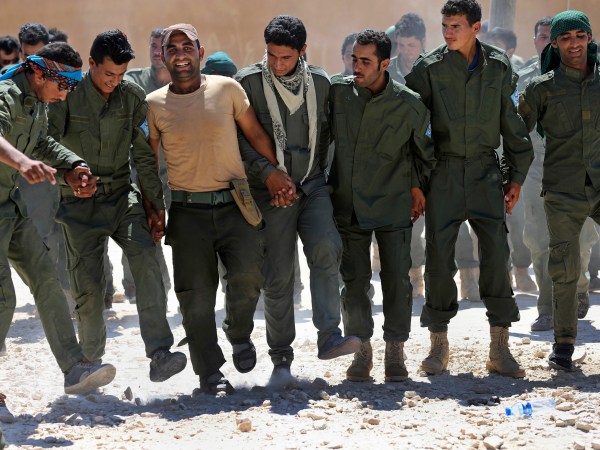 Syrian Internal Security Forces dance during their graduation ceremony, at Ain Issa desert base, in Raqqa province, northeast Syria, Thursday, July 20, 2017. Some 250 residents of Syria's Raqqa province are the latest batch to graduate from a brief U.S-training course that is preparing an internal security force to hold and secure areas as they are captured from Islamic State militants.(AP Photo/Hussein Malla)
