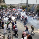 Palestinians run away from tear gas thrown by Israeli police officers outside Jerusalem's Old City, Friday, July 21, 2017. Israel police severely restricted Muslim access to a contested shrine in Jerusalem’s Old City on Friday to prevent protests over the installation of metal detectors at the holy site.. (AP Photo/Mahmoud Illean)
