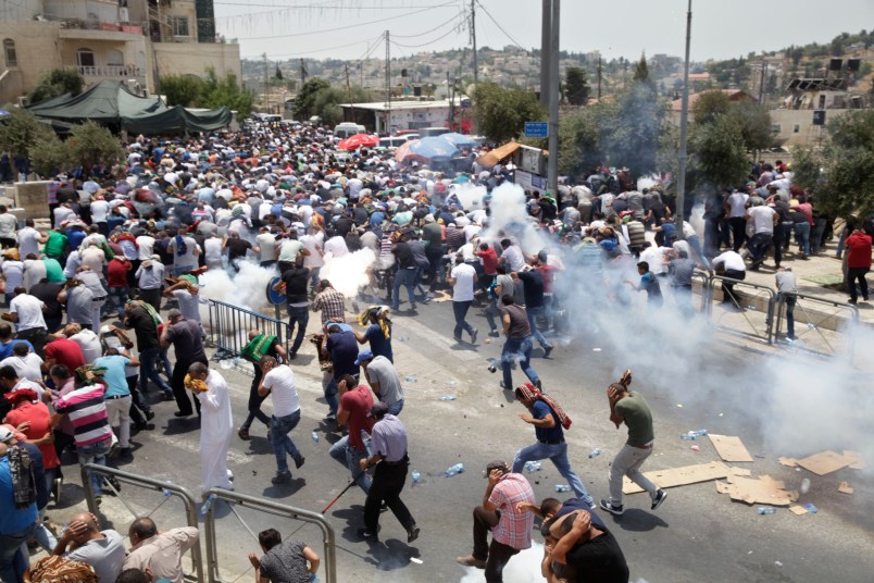 Palestinians run away from tear gas thrown by Israeli police officers outside Jerusalem's Old City, Friday, July 21, 2017. Israel police severely restricted Muslim access to a contested shrine in Jerusalem’s Old City on Friday to prevent protests over the installation of metal detectors at the holy site.. (AP Photo/Mahmoud Illean)