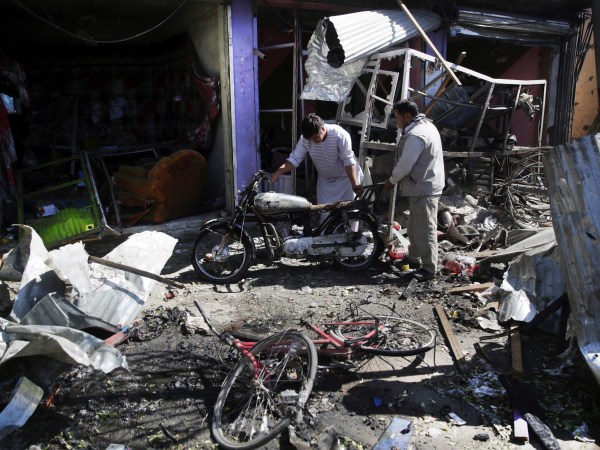 Men look at the remain of their properties at the site of a suicide attack in Kabul, Afghanistan, Monday, July 24, 2017. A suicide car bomb killed 12 people as well as the bomber and injured another 10 people early Monday morning in a western neighborhood of Afghanistan's capital where several prominent politicians reside, a government official said. (AP Photos/Massoud Hossaini)