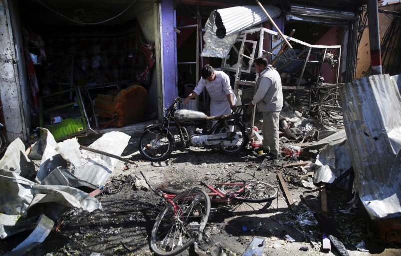 Men look at the remain of their properties at the site of a suicide attack in Kabul, Afghanistan, Monday, July 24, 2017. A suicide car bomb killed 12 people as well as the bomber and injured another 10 people early Monday morning in a western neighborhood of Afghanistan's capital where several prominent politicians reside, a government official said. (AP Photos/Massoud Hossaini)