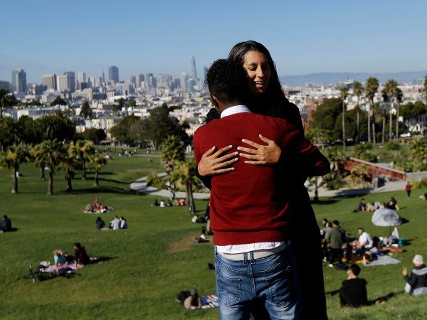 HOLD FOR STORY MOVING SUNDAY DAYSIDEIn this July 14, 2017 photo, Julie Rajagopal, facing, hugs her 16-year-old foster child from Eritrea after posing for photos at Dolores Park in San Francisco. Trump administration travel bans declared to block terrorists also are halting a small, three-decade-old program bringing orphan refugee children to waiting foster families in the United States. (AP Photo/Jeff Chiu)