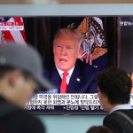 People walk by a TV screen showing a local news program reporting with an image of U.S.President Donald Trump at Seoul Train Station in Seoul, South Korea, Wednesday, Aug. 9, 2017. North Korea and the United States traded escalating threats, with President Donald Trump threatening Pyongyang "with fire and fury like the world has never seen" and the North's military claiming Wednesday it was examining its plans for attacking Guam. (AP Photo/Lee Jin-man)