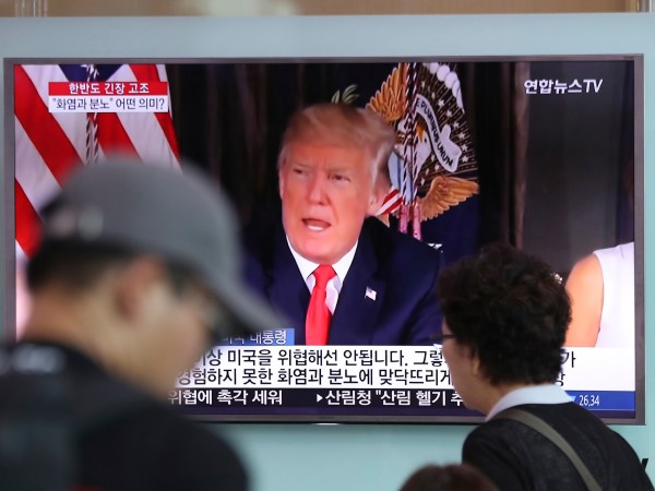 People walk by a TV screen showing a local news program reporting with an image of U.S.President Donald Trump at Seoul Train Station in Seoul, South Korea, Wednesday, Aug. 9, 2017. North Korea and the United States traded escalating threats, with President Donald Trump threatening Pyongyang "with fire and fury like the world has never seen" and the North's military claiming Wednesday it was examining its plans for attacking Guam. (AP Photo/Lee Jin-man)