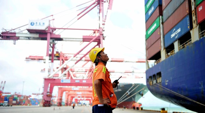 In this Tuesday, Aug. 8, 2017 photo, a worker watches as shipping containers are loaded onto a ship at a port in Qingdao in eastern China's Shandong province. China's government says it will respond to a possible trade probe ordered by President Donald Trump with "all appropriate measures" to protect Chinese interests. (Chinatopix via AP) CHINA OUT