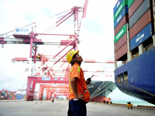 In this Tuesday, Aug. 8, 2017 photo, a worker watches as shipping containers are loaded onto a ship at a port in Qingdao in eastern China's Shandong province. China's government says it will respond to a possible trade probe ordered by President Donald Trump with "all appropriate measures" to protect Chinese interests. (Chinatopix via AP) CHINA OUT