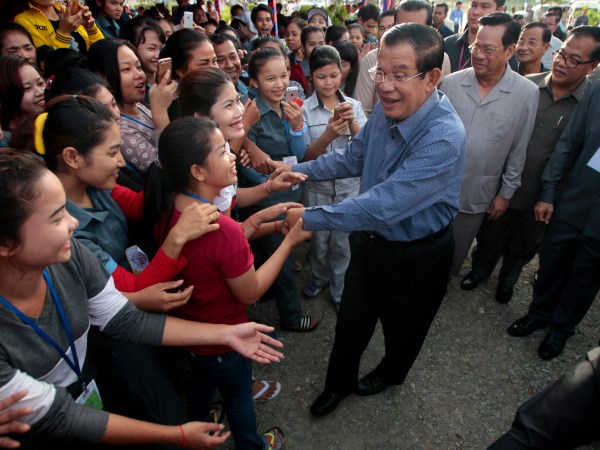 Cambodia's Prime Minister Hun Sen, center, greets garment workers during he takes a visit to Phnom Penh Special Economic Zone at the outskirts of Phnom Penh, Cambodia, Wednesday, Aug. 23, 2017. Hun Sen on Wednesday begun his plan to visit workers who work at the factories in widely Cambodia. (AP Photo/Heng Sinith)
