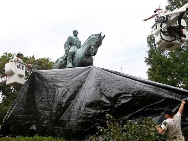 City workers drape a tarp over the statue of Confederate General Robert E. Lee in Emancipation park in Chrlottesville, Va., Wednesday, Aug. 23, 2017.  The move intended to symbolize the city's mourning for a woman killed while protesting a white nationalist rally earlier this month. (AP Photo/Steve Helber)