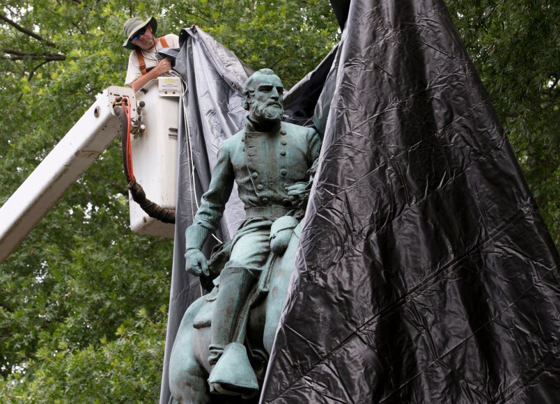 City workers drop a tarp over the statue of Confederate General Stonewall Jackson in Justice park in Chrlottesville, Va., Wednesday, Aug. 23, 2017.  The move intended to symbolize the city's mourning for a woman killed while protesting a white nationalist rally earlier this month. (AP Photo/Steve Helber)