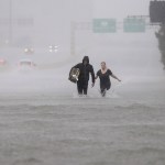 Two people walk down a flooded section of Interstate 610 in floodwaters from Tropical Storm Harvey Sunday, Aug. 27, 2017, in Houston, Texas. (AP Photo/David J. Phillip)