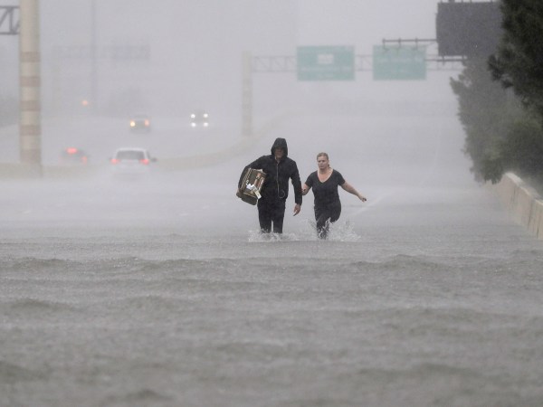 Two people walk down a flooded section of Interstate 610 in floodwaters from Tropical Storm Harvey Sunday, Aug. 27, 2017, in Houston, Texas. (AP Photo/David J. Phillip)