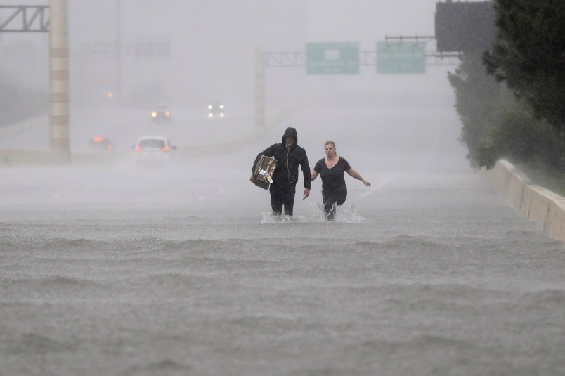 Two people walk down a flooded section of Interstate 610 in floodwaters from Tropical Storm Harvey Sunday, Aug. 27, 2017, in Houston, Texas. (AP Photo/David J. Phillip)