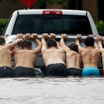 People push a stalled pickup to through a flooded street in Houston, Texas after Tropical Storm Harvey dumped heavy rains northeast Texas Sunday, Aug. 27, 2017. (AP Photo/Charlie Riedel)
