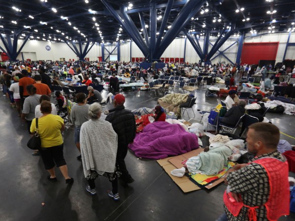 People line up for food and others rest at the George R. Brown Convention Center that has been set up as a shelter for evacuees escaping the floodwaters from Tropical Storm Harvey in Houston, Texas, Tuesday, Aug. 29, 2017. (AP Photo/LM Otero)