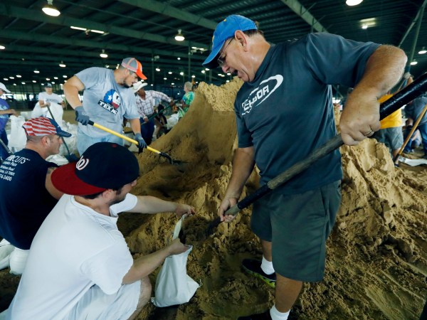 Bill Willis, right, and his son, Kyle, join other volunteers to fill sandbags for resident distributions, Tuesday, Aug. 29, 2017, at the Burton Coliseum in Lake Charles, La. (AP Photo/Rogelio V. Solis)
