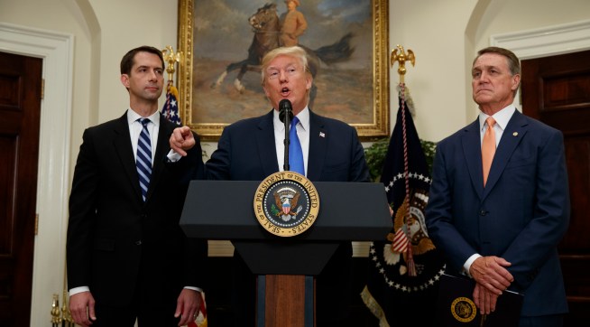 Sen. Tom Cotton, R- Ark., left, and Sen. David Perdue, R-Ga., right, look on as President Donald Trump speaks during the unveiling of legislation that would place new limits on legal immigration, in the Roosevelt Room of the White House, Wednesday, Aug. 2, 2017, in Washington. (AP Photo/Evan Vucci)