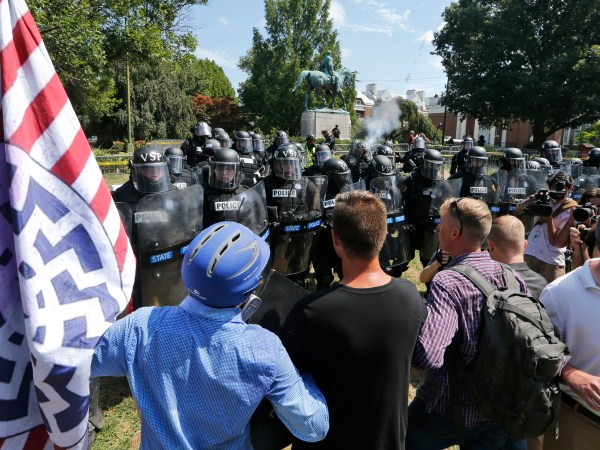 Alt Right demonstrators hold their ground against Virginia State Police as police fire tear gas rounds in Lee Park in Charlottesville, Va., Saturday, Aug. 12, 2017.  (AP Photo/Steve Helber)