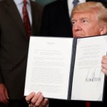 President Donald Trump holds up a signed memorandum calling for a trade investigation of China, in the Diplomatic Reception Room at the White House, Monday, Aug. 14, 2017, in Washington. (AP Photo/Alex Brandon)