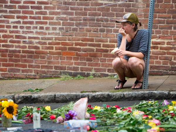 Charlottesville, VA - August 15:  A woman leaves a flower at 4th and Water Streets Tuesday, August 15 in Charlottesville, Va. where Heather Heyer was killed and 19 others were injured when a car intentionally ran through a crowd of counter protestors after the "Unite the Right" rally Saturday. (Photo by Julia Rendleman for The Associated Press)