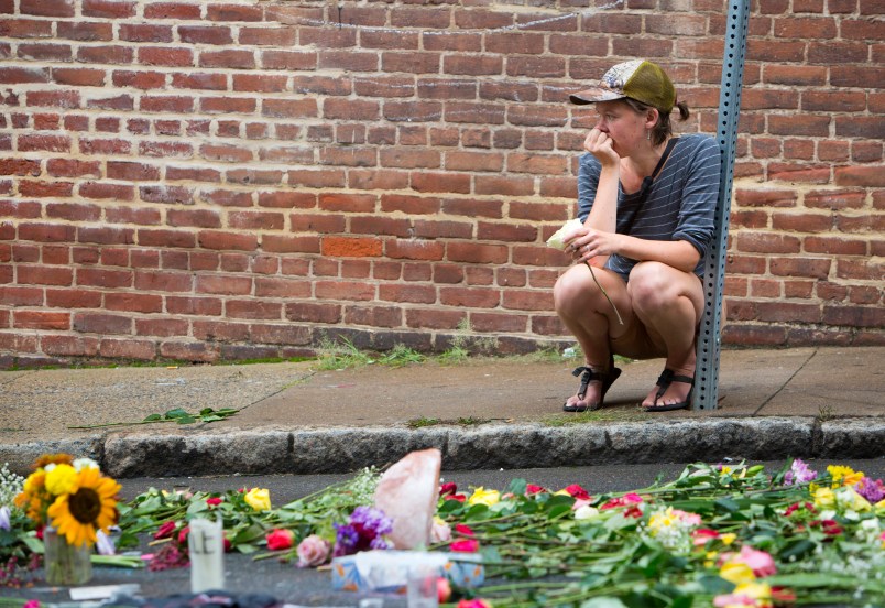 Charlottesville, VA - August 15:  A woman leaves a flower at 4th and Water Streets Tuesday, August 15 in Charlottesville, Va. where Heather Heyer was killed and 19 others were injured when a car intentionally ran through a crowd of counter protestors after the "Unite the Right" rally Saturday. (Photo by Julia Rendleman for The Associated Press)